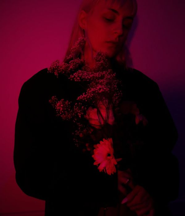 Woman meditating calmly in a dark room with a neon lime outline.